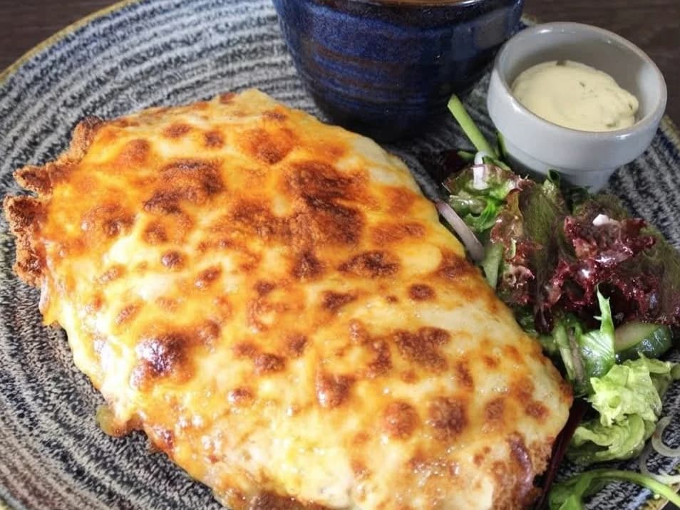 The OG Parmo - a breaded chicken parmo under a blanket of bubbling golden cheese, with a pot of chips, a side salad and a pot of dip, from Ashville Hot Chicken, JLT Dubai